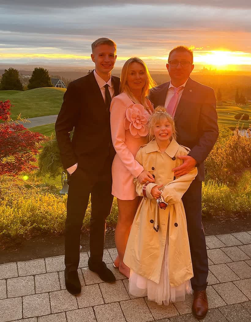 A Kirkland House Cleaners founder with his family standing together during a sunset in a garden with a scenic view.