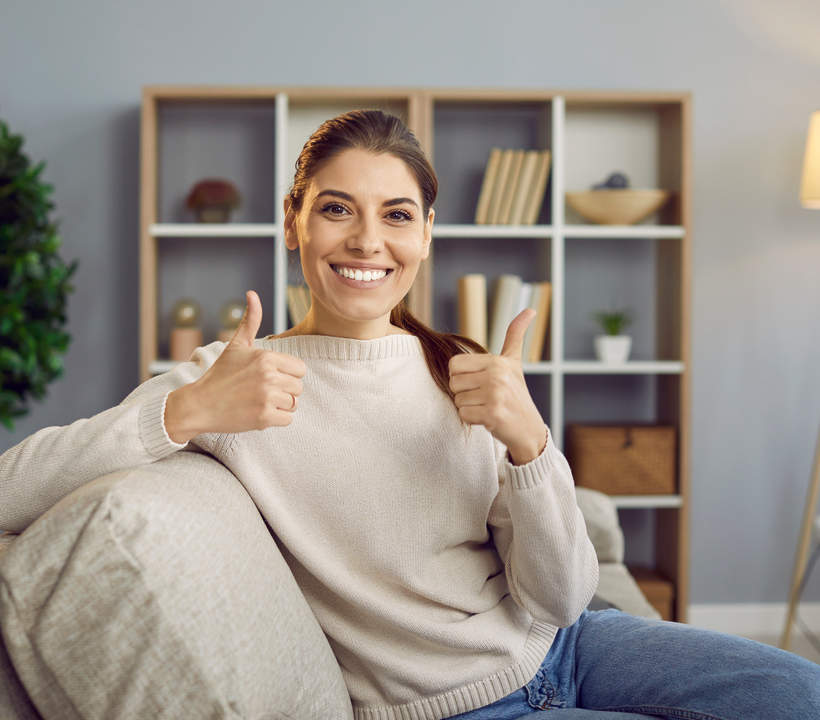 Smiling woman sitting on couch giving thumbs up after receiving a cleaning estimate in Kirkland.