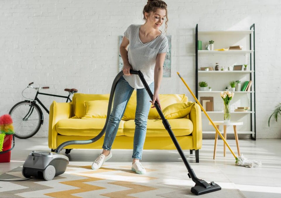 Woman vacuuming a living room rug for allergy friendly house cleaning in Kirkland, reducing dust and pet dander in an Eastside home.