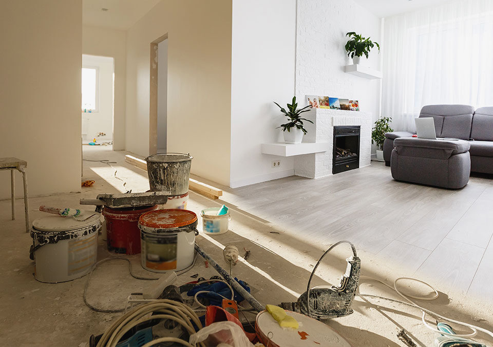 Post-construction cleaning in Kirkland, WA after home renovation, with dust, paint buckets, tools, and a newly finished living room.