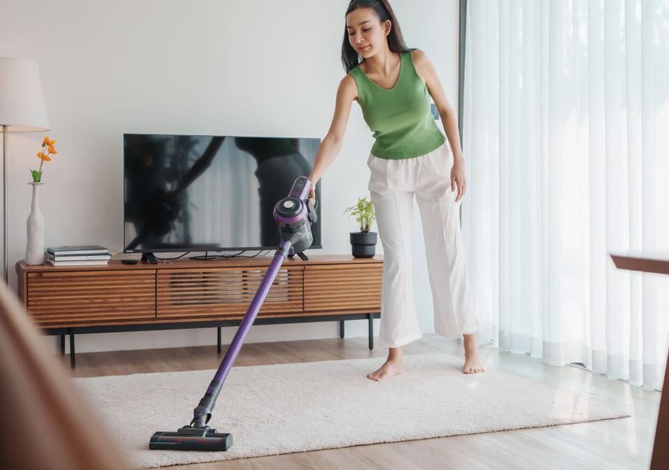 Woman vacuuming a living room rug to help reduce dust buildup in a Redmond home