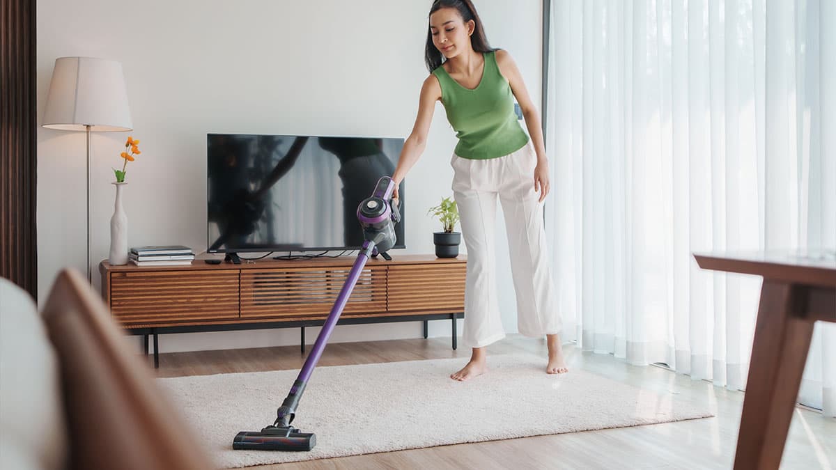 Woman vacuuming a living room rug to help reduce dust buildup in a Redmond home