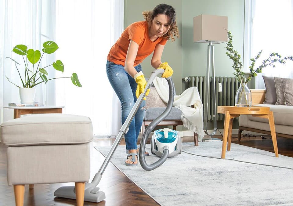 Woman vacuuming a living room rug during summer house cleaning in a Sammamish home