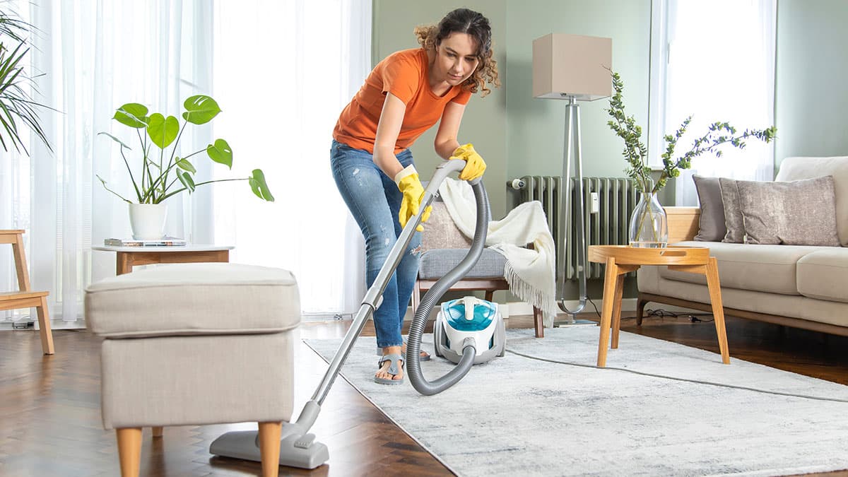 Woman vacuuming a living room rug during summer house cleaning in a Sammamish home
